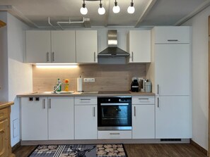A modern kitchen with white cabinets, a built-in oven, and a coffee maker. - Alpine House in Prebl Near Klippitztorl Ski Area (Wolfsberg)