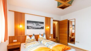 A modern bedroom with a bed, wooden headboard, bedside tables, a large mirror, and a framed picture on the wall. - Apartment in Serfaus-fiss-ladis (Ladis)