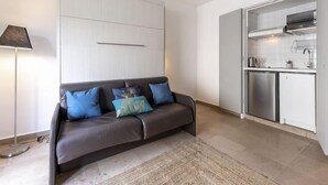 A modern living room with a dark brown sofa, a small rug, and a kitchen area with stainless steel appliances. - Le Marlyne 2 by Interhome (Cannes)