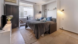 A modern bedroom with a bed, bedside tables, a TV, and a window with a view of the outside. - Le Marlyne 2 by Interhome (Cannes)
