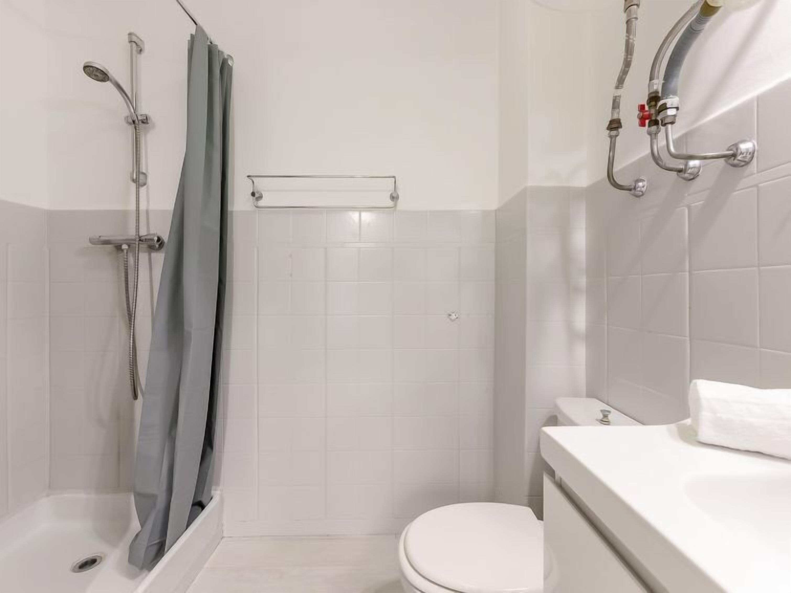 Une salle de bain avec douche, toilettes et baignoire.