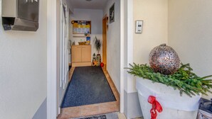 A hallway with a door leading to a kitchen, a wall-mounted thermostat, and a decorative plant with pinecones. - Inviting Apartment in Fiss in the Mountains (Fiss)