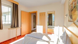 A hotel room with a bed, a desk, a mirror, and a window with curtains. - Inviting Apartment in Fiss in the Mountains (Fiss)