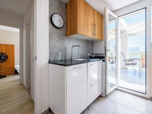 Eine moderne Küche mit weißen Schränken, einer schwarzen Arbeitsplatte, einer Edelstahl-Spüle und einer Holzbalkendecke.