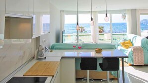 Ein modernes Hotelzimmer mit Balkon, Essbereich und Küchenzeile.