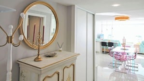Ein modernes Interieur mit einer Marmorkonsole, einem goldgerahmten Spiegel und einem rosa Tisch mit Stühlen.