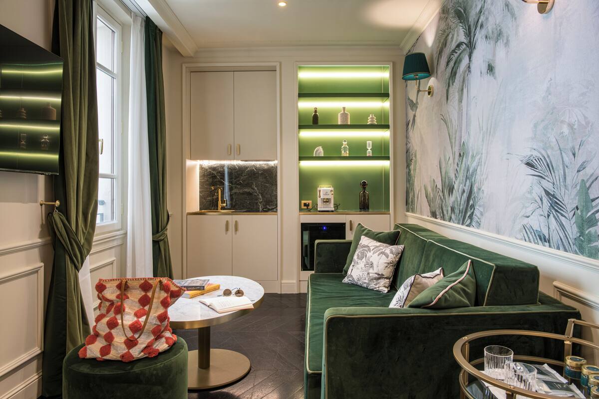 A modern living room with a green sofa, a round coffee table, and a wall-mounted shelf with decorative items.