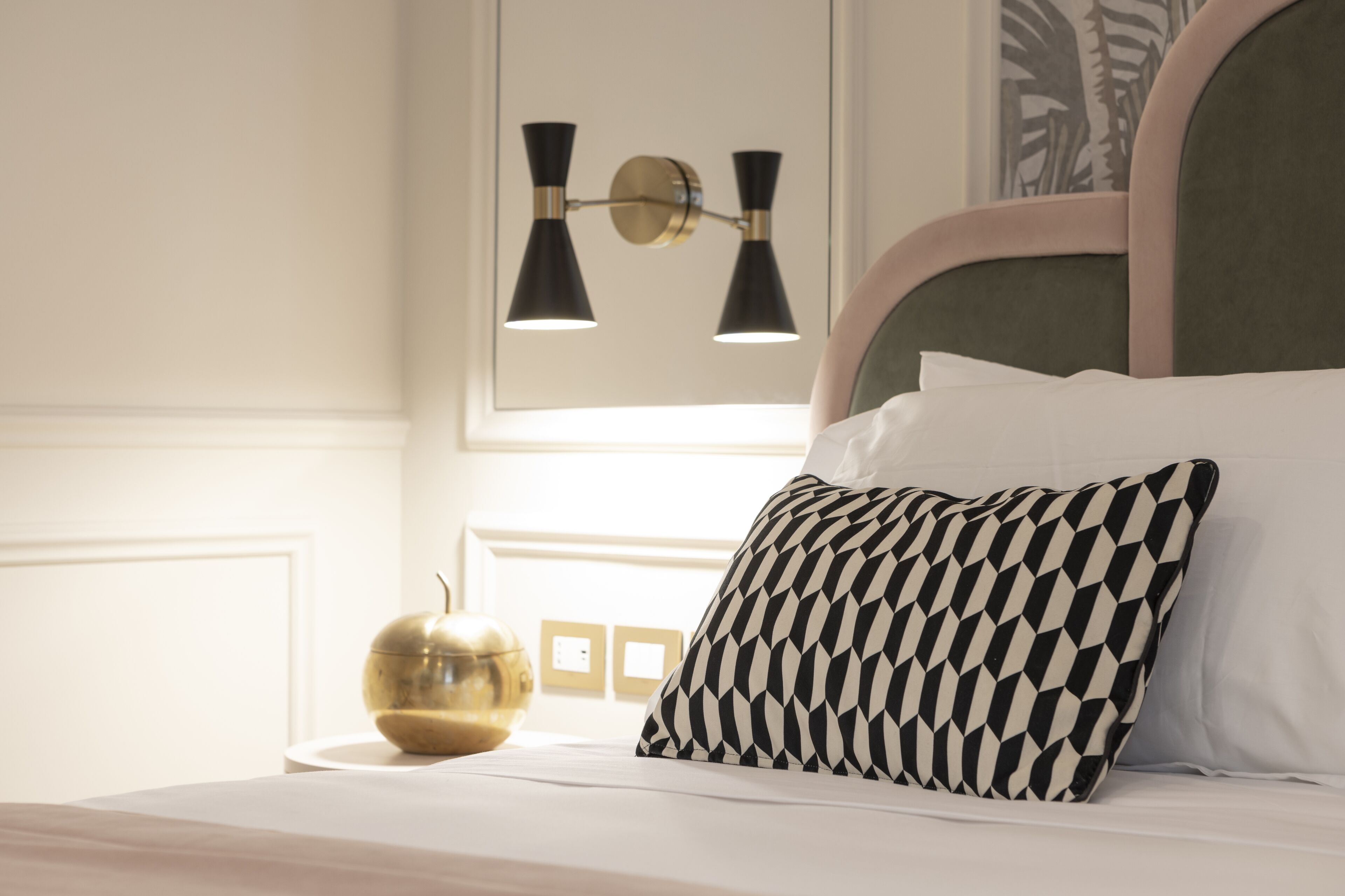 A neatly made bed with a patterned pillow, a bedside lamp, and a decorative globe on a white bedside table.