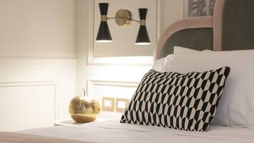 A neatly made bed with a patterned pillow, a bedside lamp, and a decorative globe on a white bedside table.