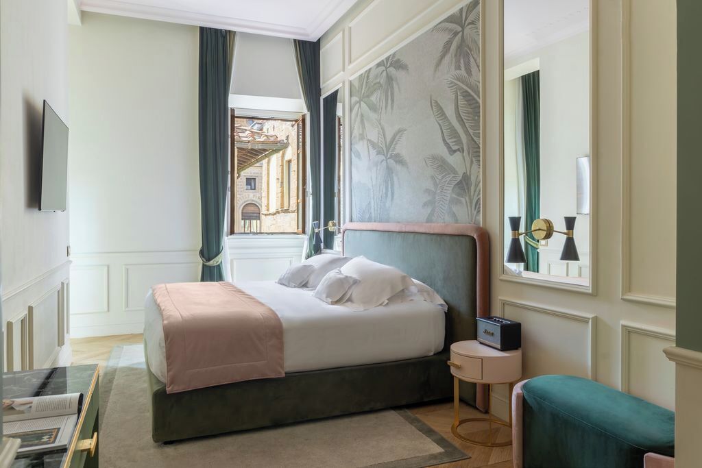 Una habitación de hotel con cama, mesita de noche, televisor y vista a un patio.