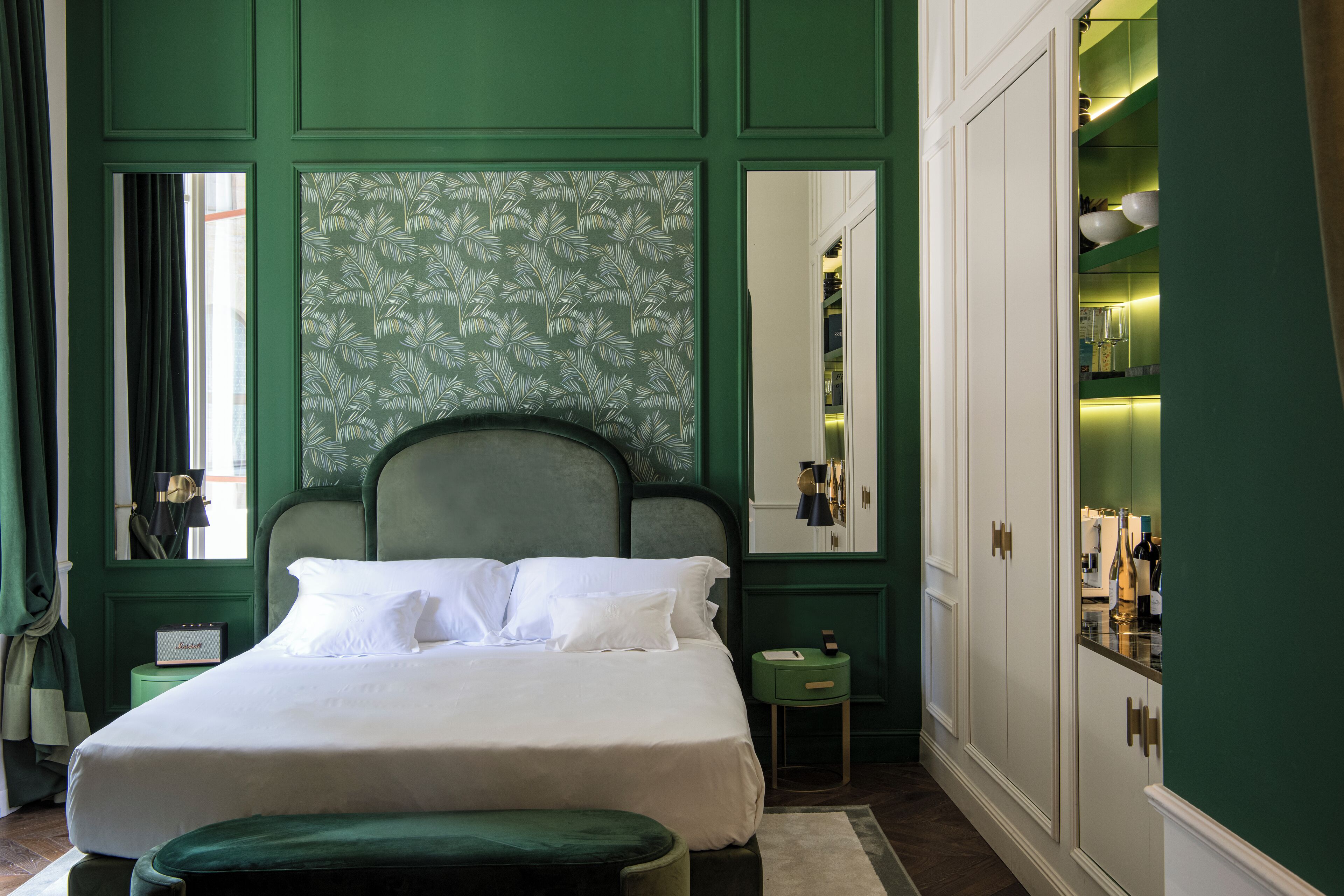 A neatly arranged bedroom with a large bed, a bedside table, a nightstand, and a wardrobe.