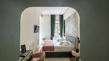 Une chambre d’hôtel avec un lit, un bureau avec un ordinateur, une chaise, une table de chevet avec une lampe, et une vue sur l’extérieur, visible à travers l’encadrement d’une porte.