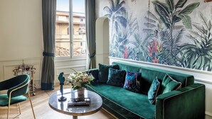 A living room with a green sofa, a round coffee table, a decorative bird statue, and a tropical mural on the wall. - Hotel La Gemma (Florence)