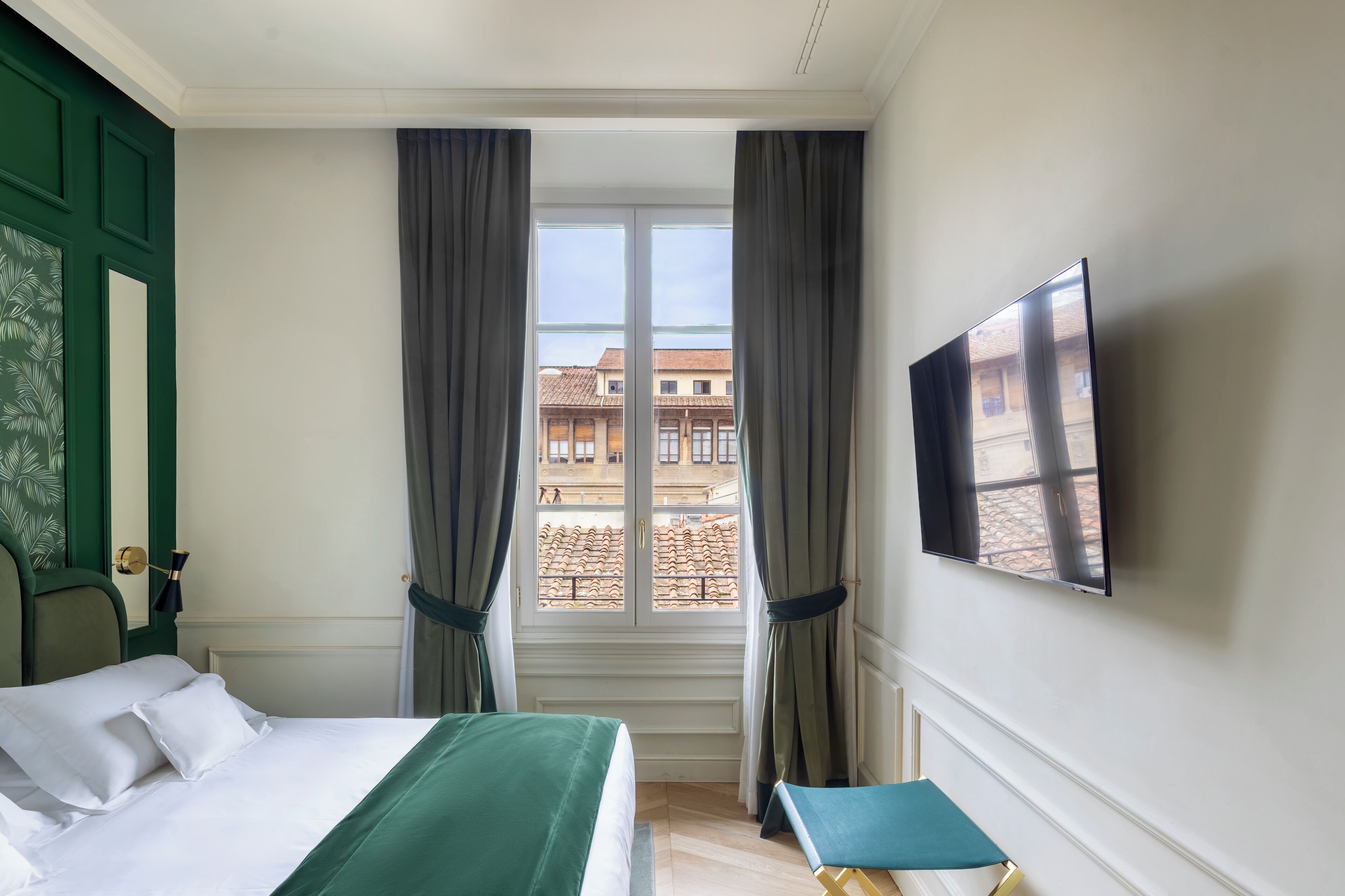 A hotel room with a bed, a chair, a TV, and a window with curtains.