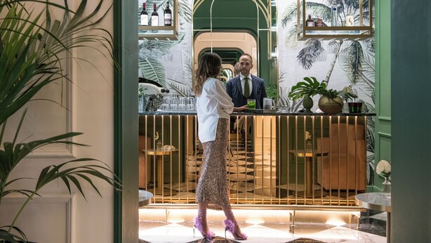 A bar area with a counter, shelves with bottles, and a mirrored wall reflecting the scene. - Hotel La Gemma (Florence)