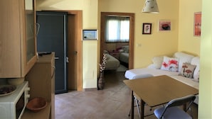 Un espacio habitable compacto con kitchenette, zona de comedor y sofá.
