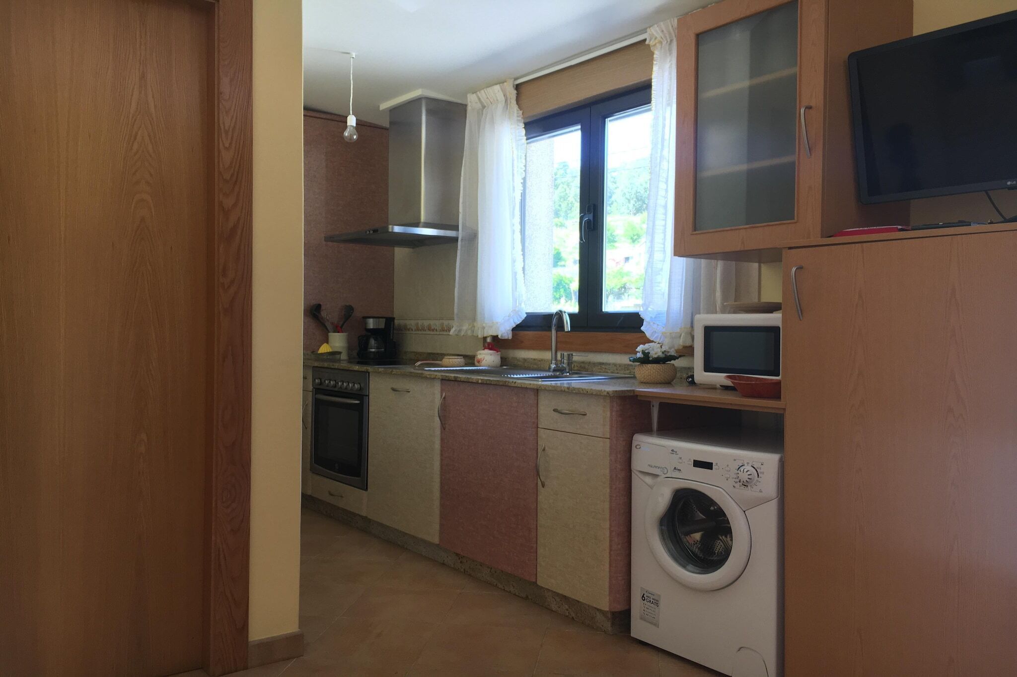 Uma cozinha compacta com forno embutido, micro-ondas e máquina de lavar.