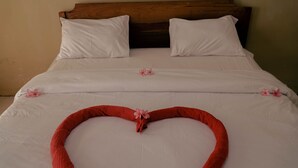A neatly made bed with white linens and a heart-shaped pillow arrangement. - Indonesia Backpacker Hostels  (Kuta)