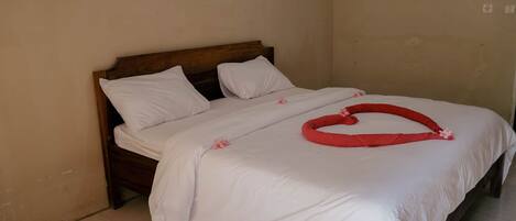 A neatly made bed with white linens and a red decorative item on the bed.