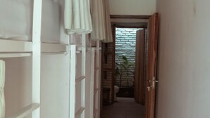A narrow hallway with a white air conditioning unit on the wall, a wooden door at the end, and a tiled floor. - Indonesia Backpacker Hostels  (Kuta)