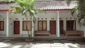A building with a tiled roof, wooden doors, and benches. - Indonesia Backpacker Hostels  (Kuta)