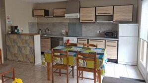 Uma cozinha moderna com armários de madeira, uma mesa de jantar com cadeiras, um micro-ondas e uma geladeira.