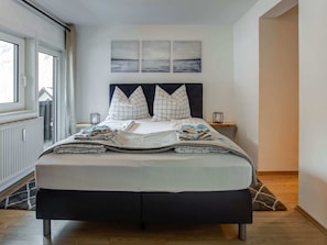 A neatly made bed with a checkered pillow, a bedside table with a lamp, and a window with curtains. - Apartment Feld am See Near Ski Slopes (Feld am See)