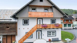 A two-story building with a wooden staircase, a balcony with flower boxes, and a small front porch. - Apartment in Bad Mitterndorf Near ski Area (Bad Mitterndorf)