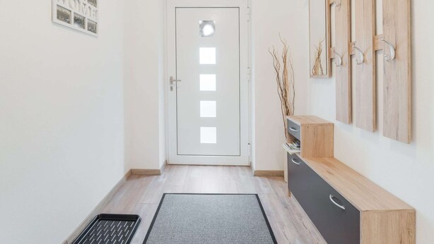 A hallway with a white door, a small cabinet with a drawer, and a wall-mounted wooden rack with hooks. - Apartment in Bad Mitterndorf Near ski Area (Bad Mitterndorf)