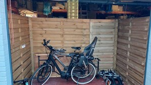 Un petit espace clos avec un mur en bois, un sol rouge et deux vélos.