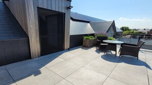 Une terrasse sur le toit comprenant un espace repas, une structure en bois et des plantes en pot.