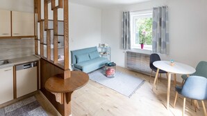 Ett modernt kök med träskåp, en inbyggd diskmaskin och en matplats med ett runt träbord och två stolar.