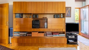 Una sala de estar moderna con un mueble de entretenimiento de madera, un televisor de pantalla plana y una estantería.