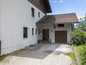 A two-story house with a tiled roof, a wooden door, and a small porch with potted plants. - Apartment in Seeboden by Lake Millstatt (Seeboden)