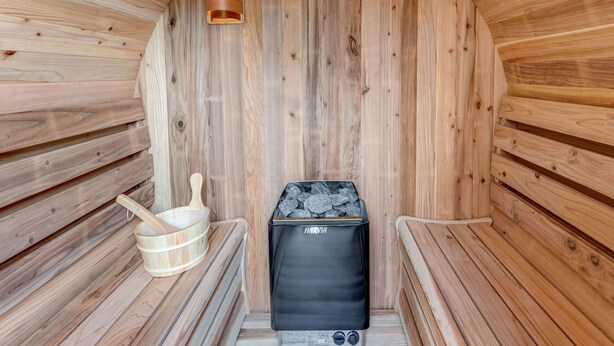 Una sauna con paredes de madera, un banco, un calentador y un cubo.