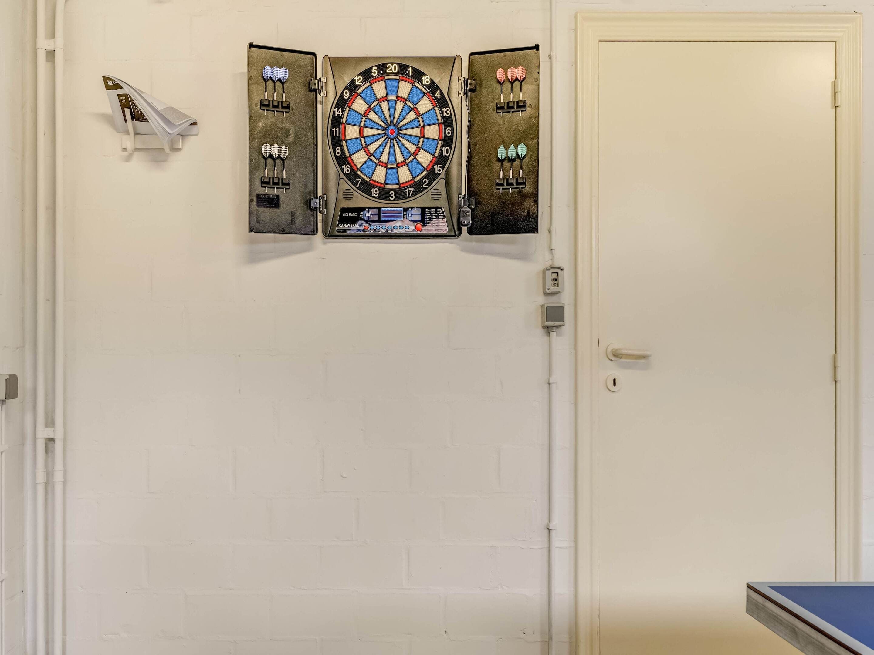 A dartboard mounted on a white brick wall with a closed door to the right.