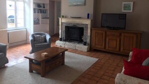 Una sala de estar con chimenea, televisor, estantería y sofá rojo.