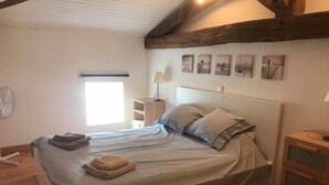 Un dormitorio con cama, mesitas de noche, ventana y decoración en la pared.