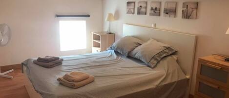 A bedroom with a bed, bedside tables, a window, and wall art.