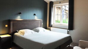 A hotel room with a bed, nightstands, a window with curtains, and a chair. - Vlaanderen Cozy Cottage (Maasmechelen)