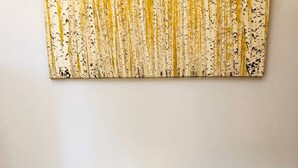 Ein gelber Sessel mit Holzbeinen vor einer strukturierten Wand.