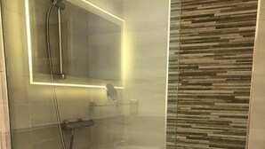 Ein modernes Badezimmer mit einer Duschkabine aus Glas, einem weißen Waschbecken und einer Badewanne.