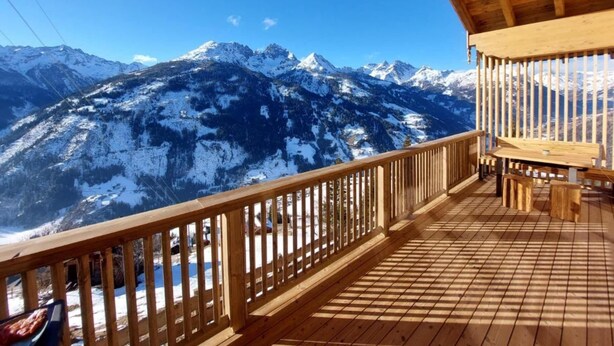 A wooden deck with a view of snow-covered mountains.