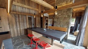 A rustic kitchen with a stone floor, wooden walls, and a central island with bar stools.