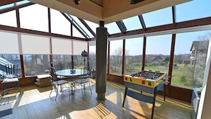 A spacious room with a large window, a round table with chairs, and a foosball table. - Holiday Home in Noiseux With BBQ Terrace (Somme-Leuze)