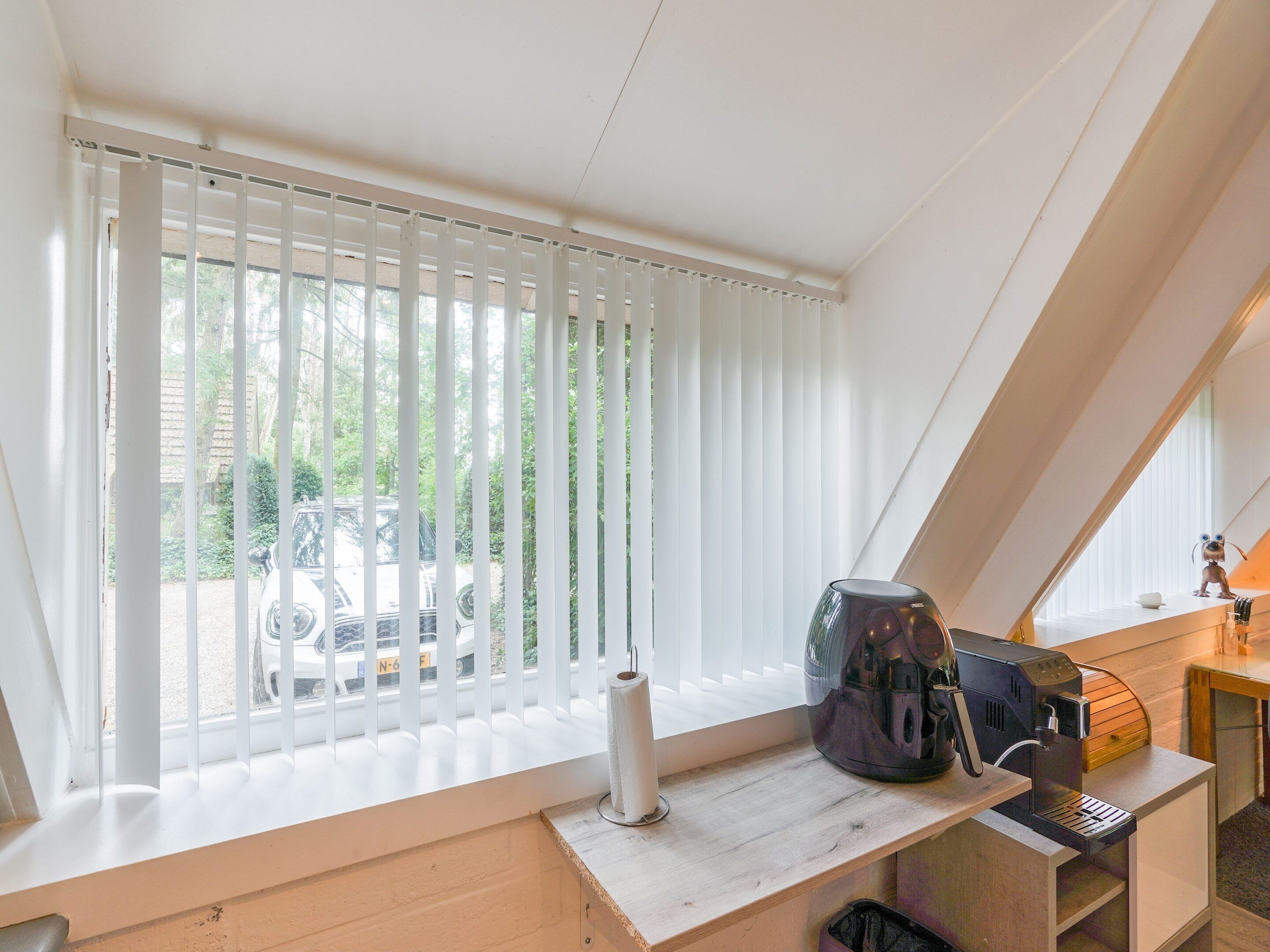 A room with a window, a coffee machine, and a small table.