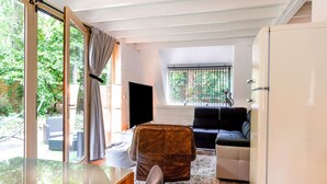A modern living room with a glass table, leather armchair, and black sofa. - Welcoming Chalet in Rekem Tucked in Nature (Lanaken)