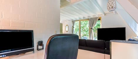 Un espacio habitable moderno con una pared de ladrillo blanco, un televisor de pantalla plana, un sofá y una zona de comedor.