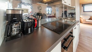 A modern kitchen with a coffee maker, toaster, and utensils on the counter. - Holiday Home in Leglise With Garden (Léglise)