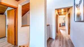 A hallway with wooden flooring and white walls, leading to a dining area with a table and chairs. - Holiday Home in Leglise With Garden (Léglise)